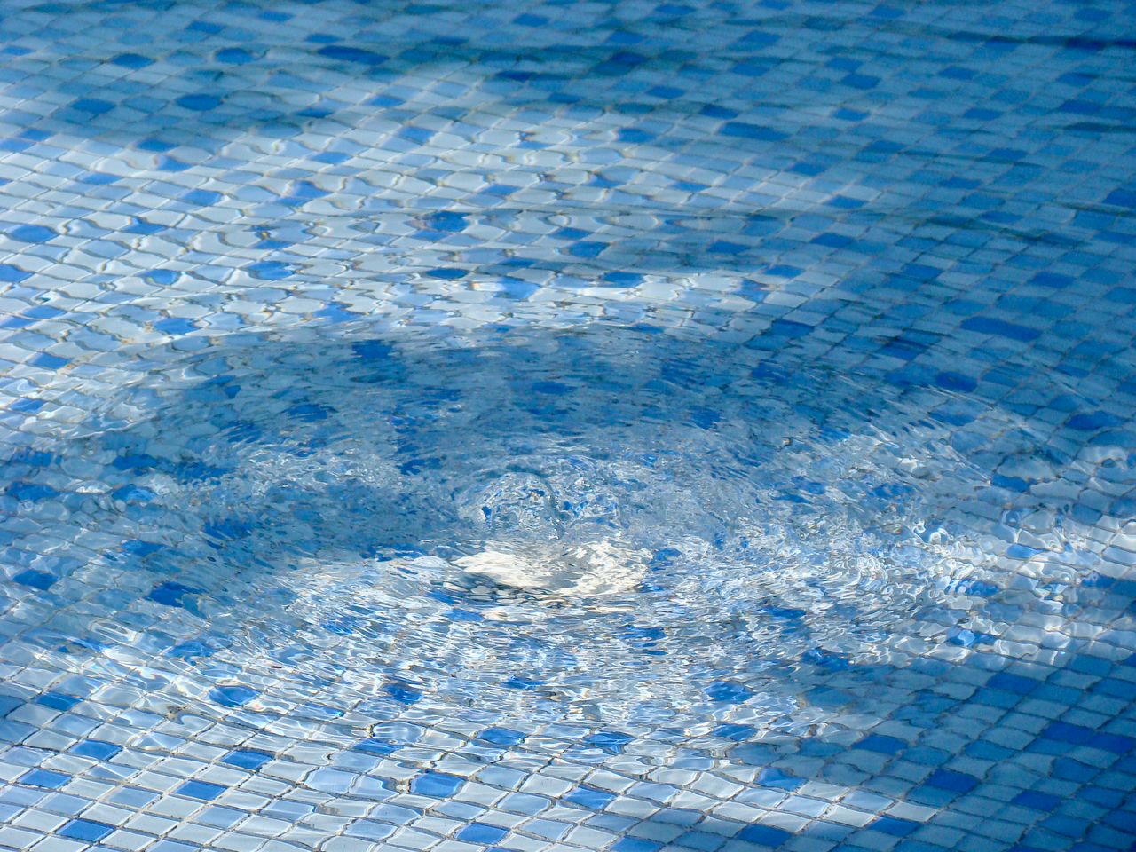 Close-up view of a blue mosaic-style fiberglass pool finish creating a vibrant and luxurious water appearance.