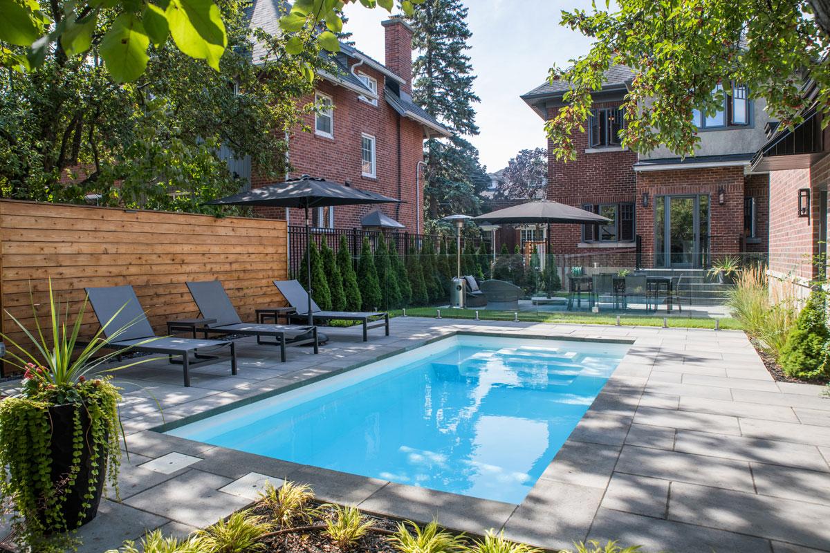 Completed fibreglass pool with pavers and backyard landscaping
