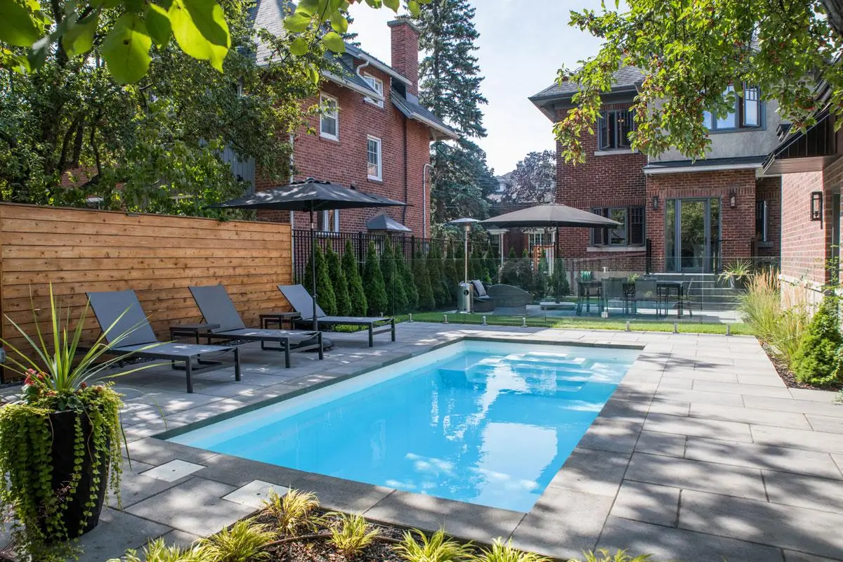 Completed fibreglass pool with pavers and backyard landscaping